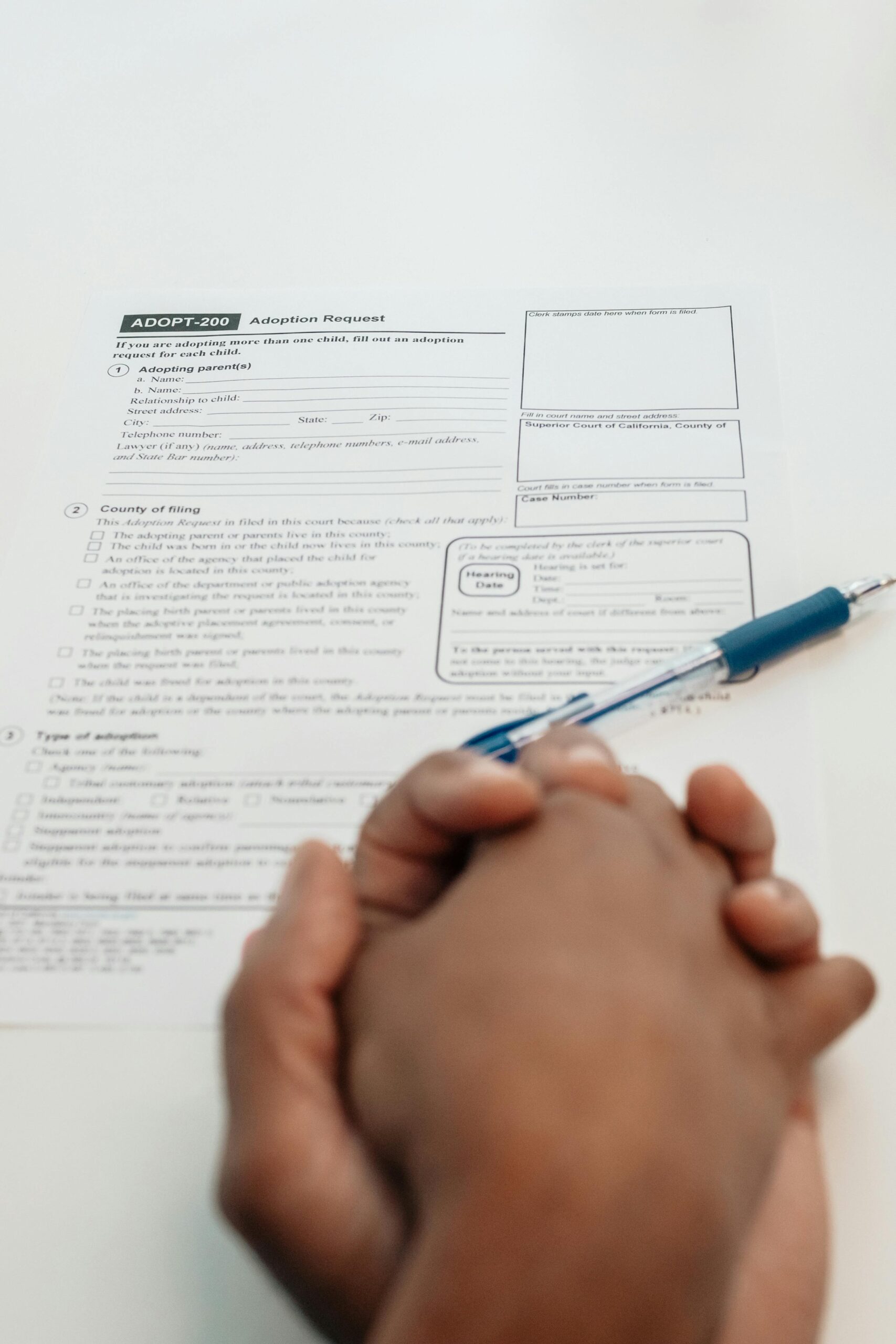 Close-up of hands holding a pen over an adoption request form. Concept of adoption paperwork.